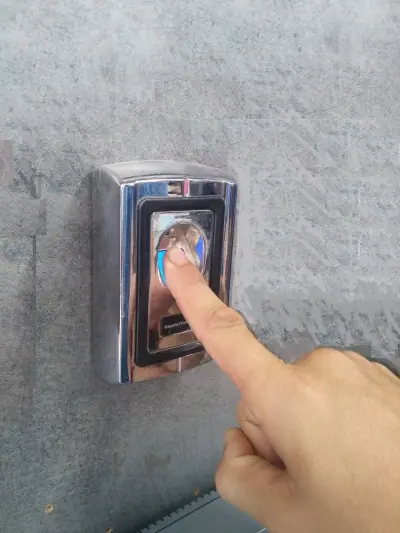 קורא טביעת אצבע ביומטרי בגימור כרום מותקן על קיר ליד דלת כניסה