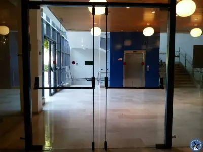 ידית בהלה כפולה מותקנת על דלתות זכוכית בלובי כניסה של בניין משרדים