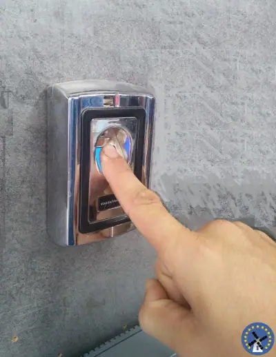 קורא טביעת אצבע בפאנל כרום מבריק לבקרת כניסה לצד דלת מאובטחת