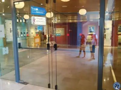 מנעול צילינדר בדלת זכוכית בכניסה רחבה ומוארת של מבנה ציבורי מרווח
