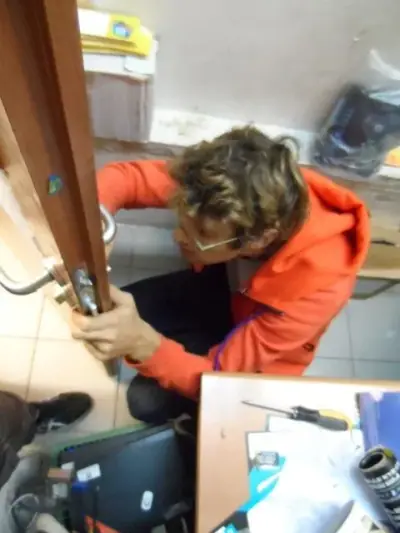 מנעולן כורע מול הדלת ומתקן את מנגנון המנעול בעבודת שטח