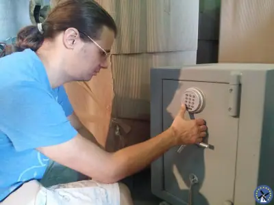 פורץ כספות מקליד קוד על לוח מקשים דיגיטלי של כספת בזמן פתיחה