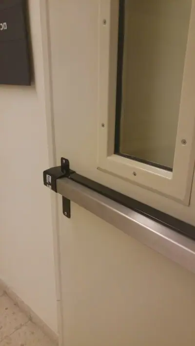 תושבת ידית בהלה מקובעת על דלת מזוגגת כחלק ממערכת יציאת חירום