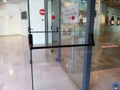 ידית בהלה עם מוט דחיפה אופקי על דלת זכוכית של בית עסק