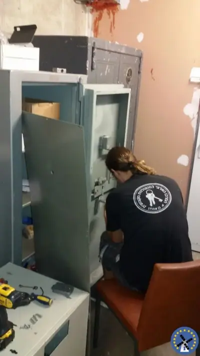 פורץ כספות לצד כספת רצפה פתוחה ודלתה פתוחה לאחר פתיחה מוצלחת
