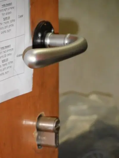 ידית מנוף כסופה עם צילינדר חשוף רגע לפני סיום ההתקנה בדלת